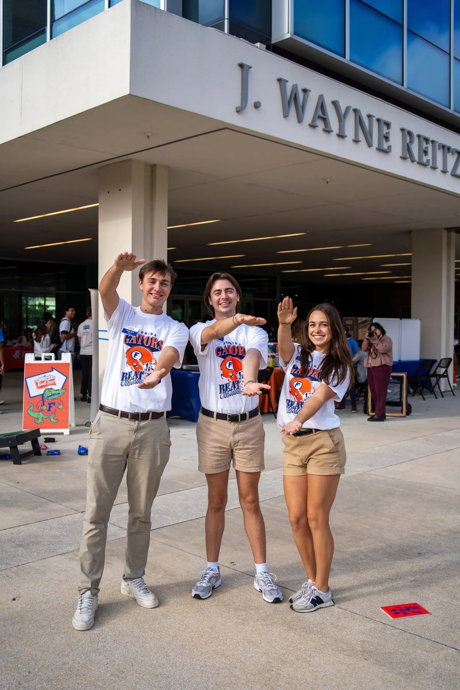 Three students do the Gator Chomp outside the J. Wayne Reitz Union.