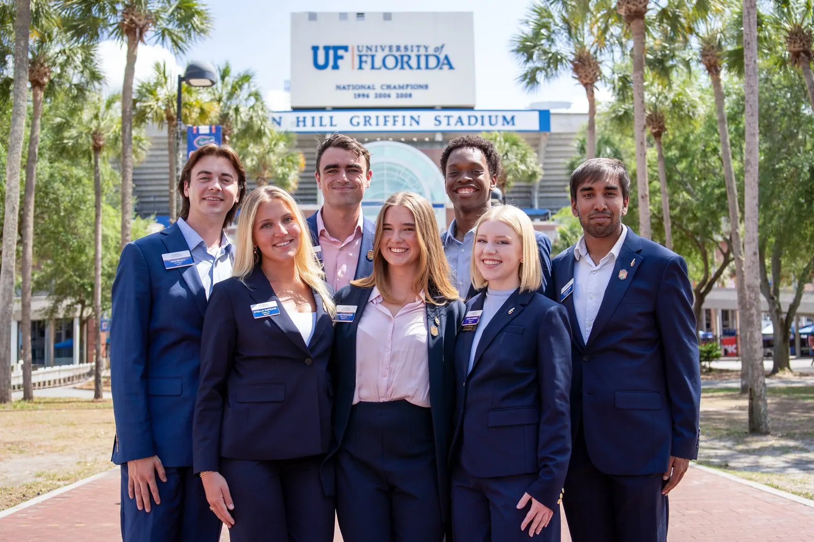 A student organization in navy blazers poses in front of Ben Hill Griffin Stadium.