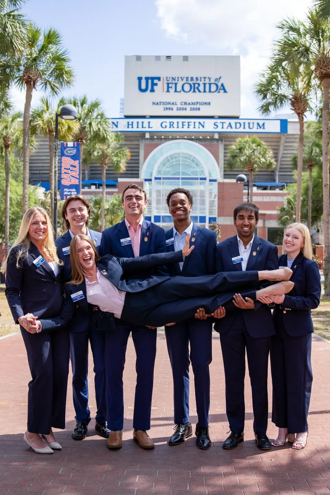 The organization holds one member horizontally across the group in front of Ben Hill Griffin Stadium.