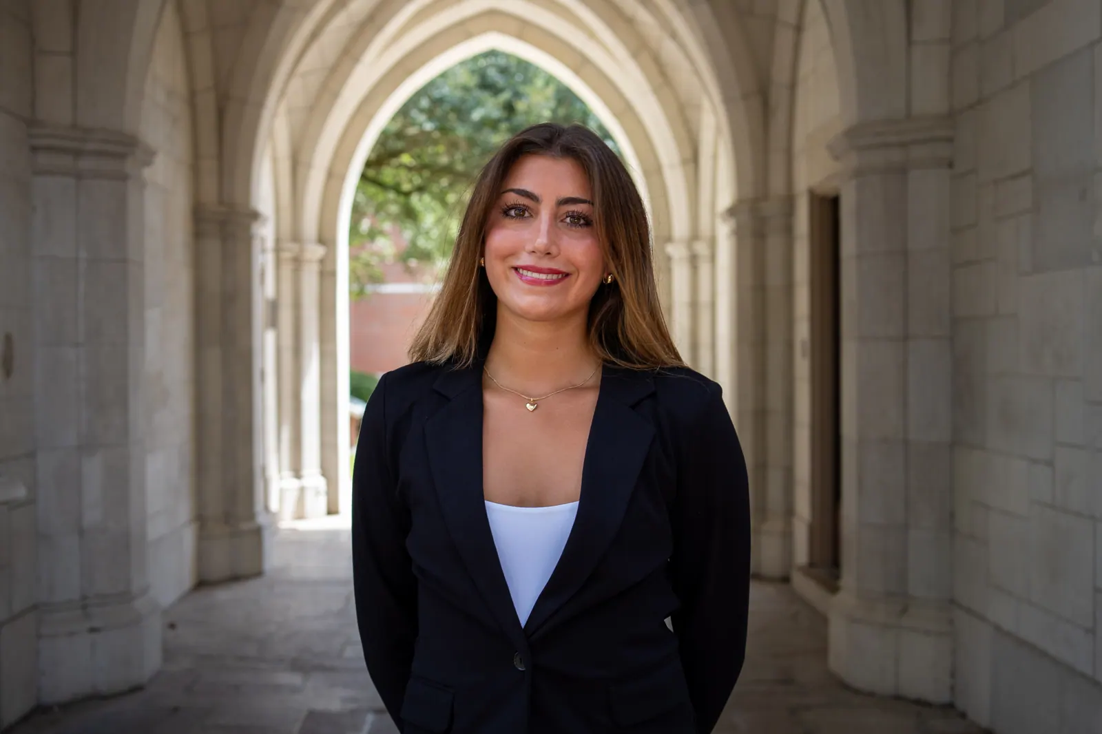 Headshot of a young woman in a black blazer framed by a pointed stone arch.