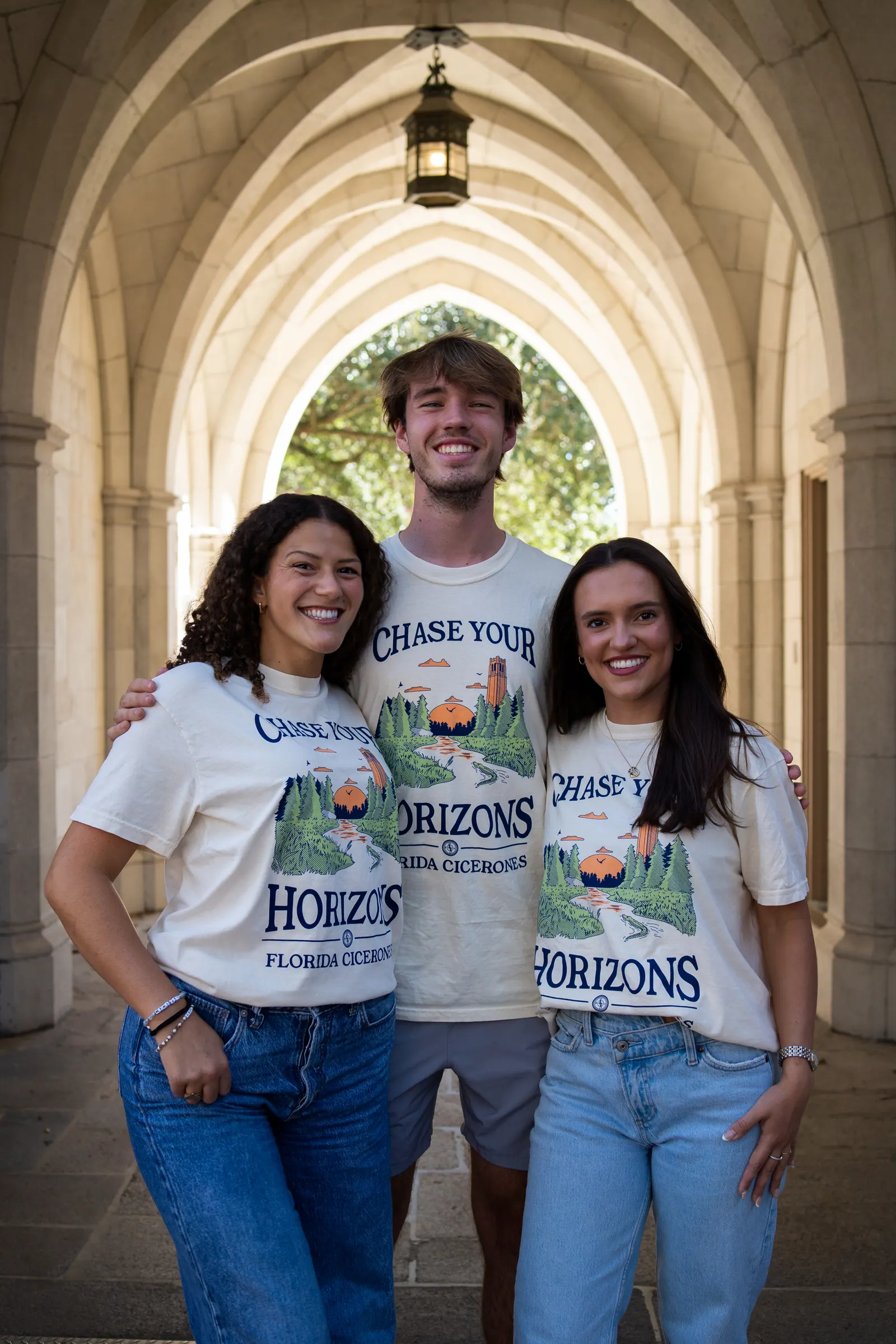 Three Cicerones members stand together under a lantern in a stone corridor.