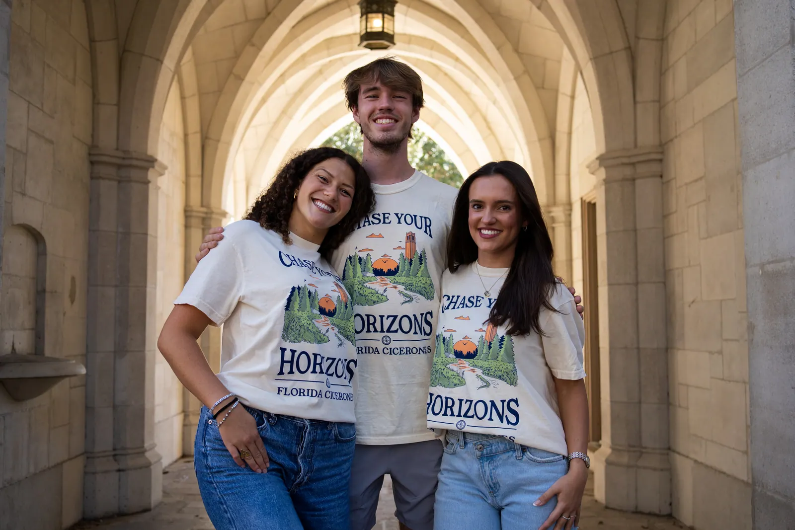 Three Cicerones members lean in and laugh under a stone archway.