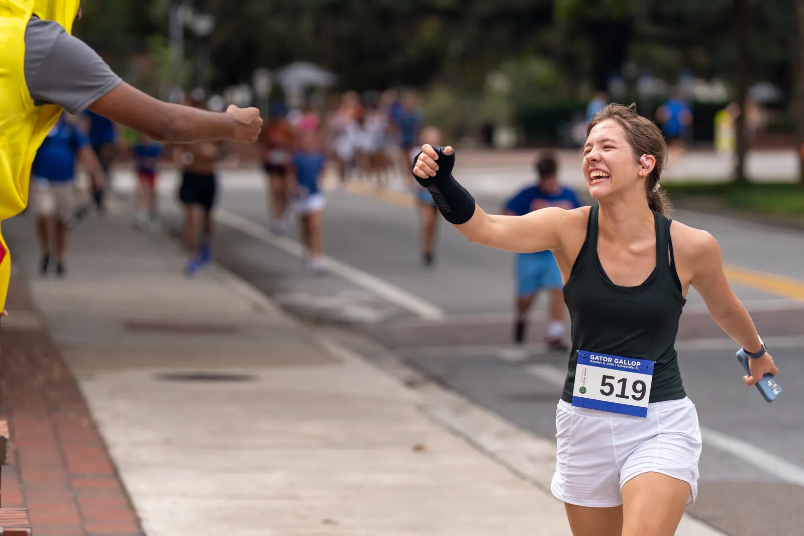 A smiling runner reaches out for a fist bump from a volunteer along the course.