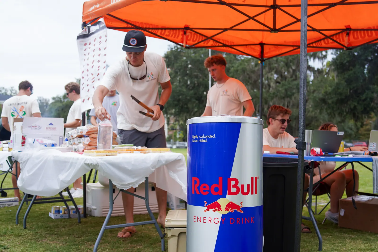 Club members cook and plate food under the orange tent.