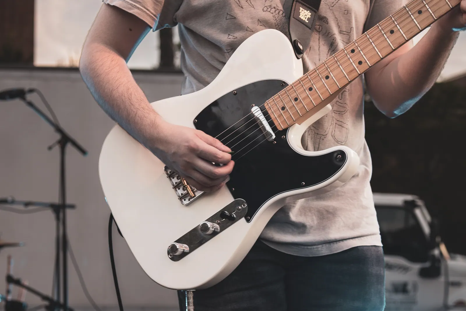 Detail of a hand strumming a white Telecaster.