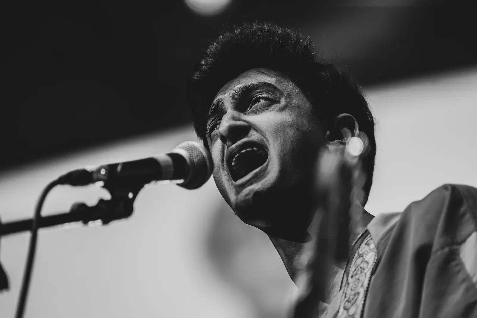 Black and white close-up of a singer straining into the microphone.