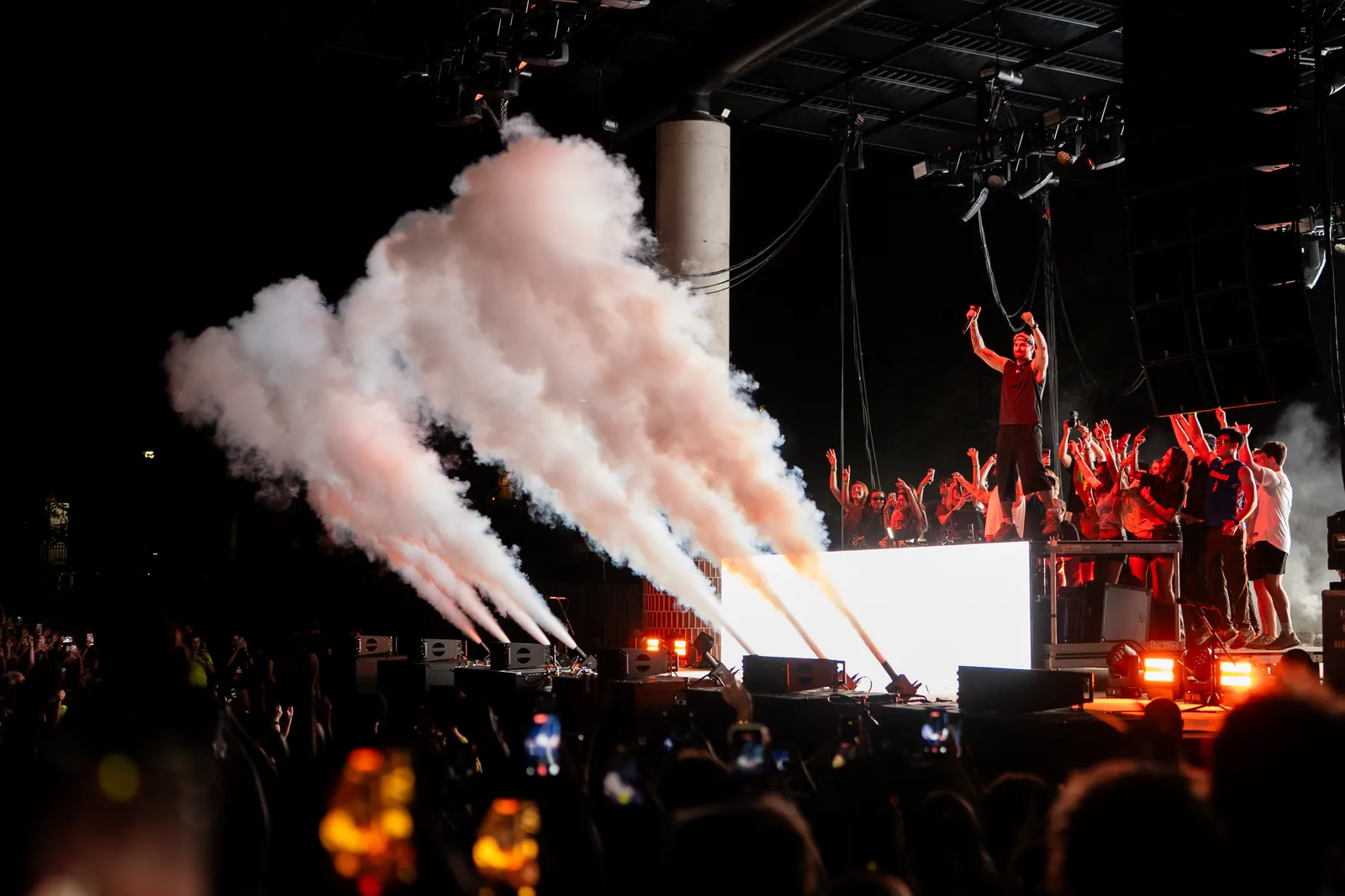 CO2 cannons fire white plumes across the Swamp Fest stage as the crowd raises their hands at night.